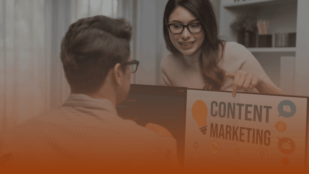 Whissel Strategies A woman points to a "Content Marketing" sign on a monitor while talking to a man seated at a desk in an office setting. Toronto Digital Marketing Agency