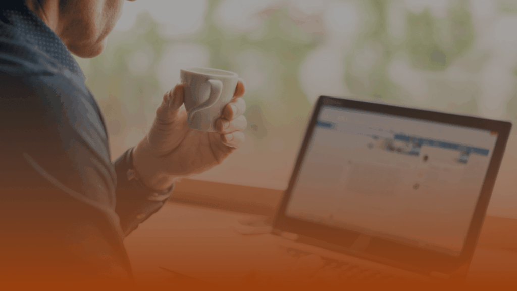 Whissel Strategies Person holding a white mug while looking at a laptop screen; the image has an orange gradient overlay at the bottom. Toronto Digital Marketing Agency