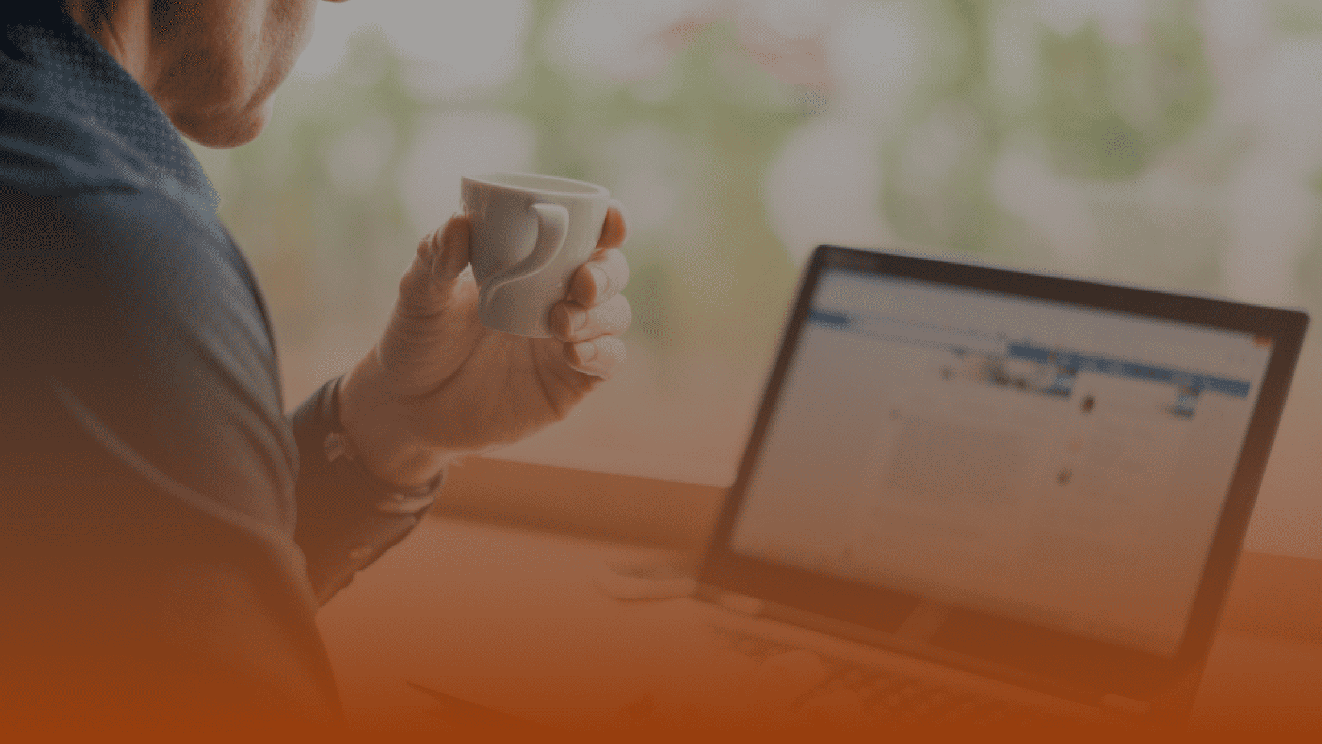 Whissel Strategies Person holding a white mug while looking at a laptop screen; the image has an orange gradient overlay at the bottom. Toronto Digital Marketing Agency