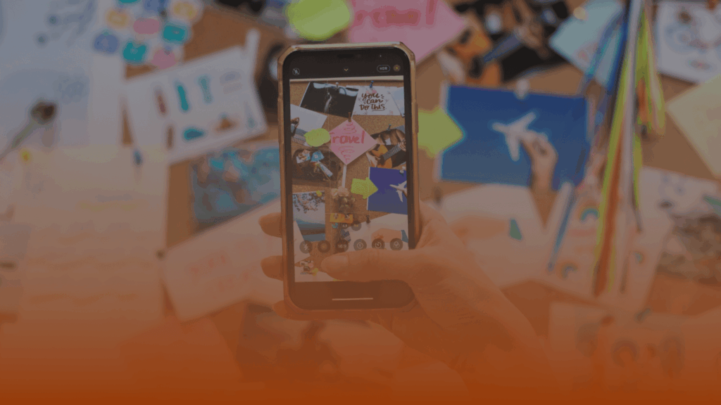 Whissel Strategies A hand holds a smartphone taking a photo of a creative collage board filled with colorful cutouts, notes, and images pinned to it. Toronto Digital Marketing Agency