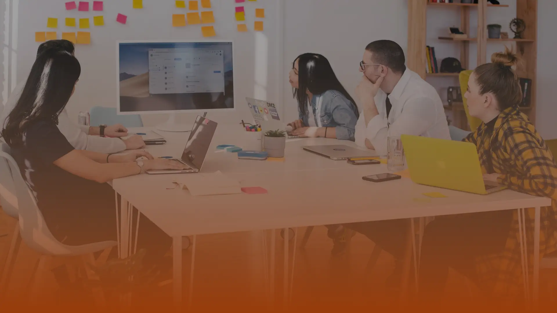 Whissel Strategies Five people sit around a table with laptops, watching a presentation on a large monitor in a modern office with sticky notes on the wall. Toronto Digital Marketing Agency