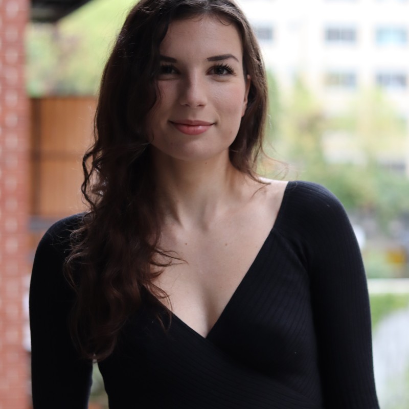 Whissel Strategies A woman with long brown hair wearing a black long-sleeve top stands outside in front of a blurred urban background. Toronto Digital Marketing Agency