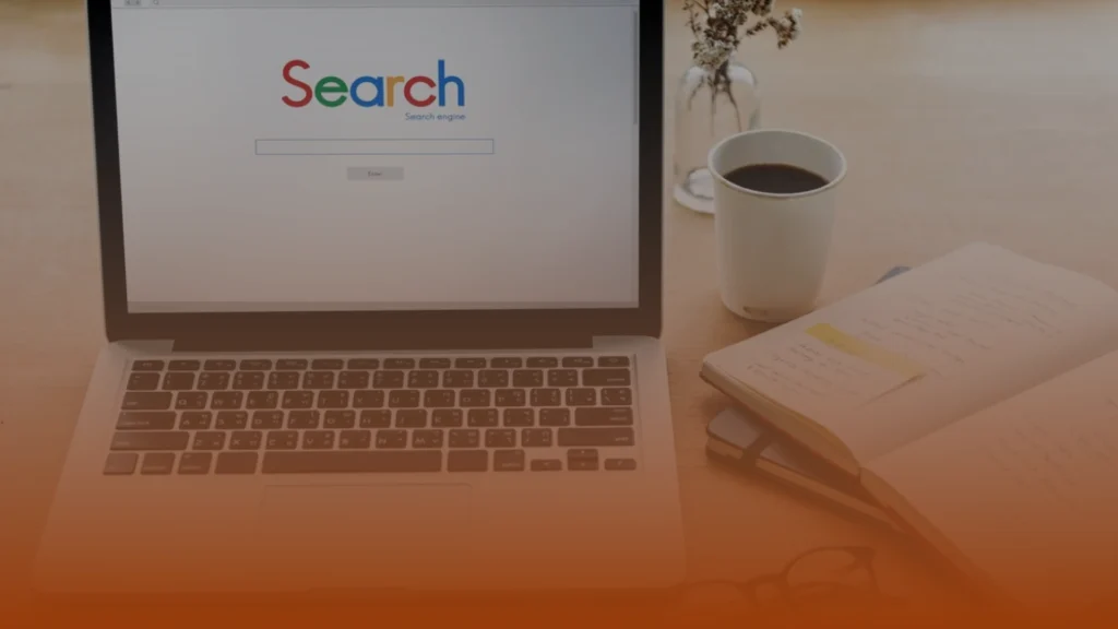 Whissel Strategies A laptop displaying a search engine homepage sits on a desk beside a cup of coffee, a vase with dried flowers, and an open notebook with notes. Toronto Digital Marketing Agency