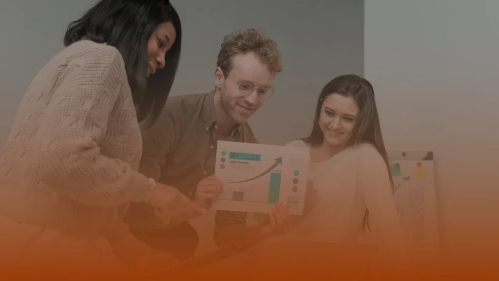 Whissel Strategies Three people look at a printed chart with graphs and data in an office setting, appearing to discuss the document together. Toronto Digital Marketing Agency