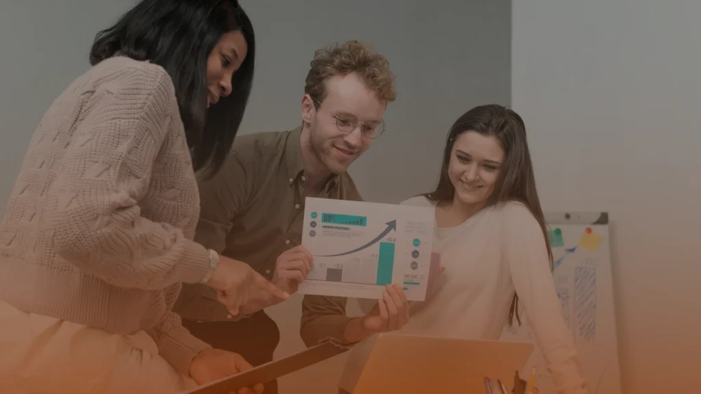 Whissel Strategies Three people look at a laptop while one of them holds a printed chart with graphs and data. Toronto Digital Marketing Agency