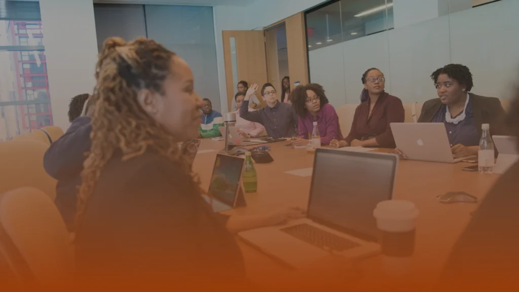 Whissel Strategies A group of people sit around a conference table with laptops and notebooks, engaged in a meeting in a modern office setting. Toronto Digital Marketing Agency