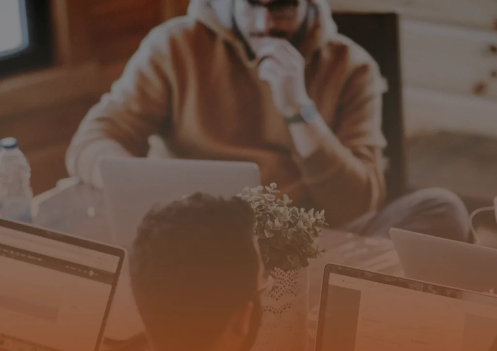 Whissel Strategies Three people work at laptops around a table, one with a hand on their chin. A small potted plant sits in the center of the table. Toronto Digital Marketing Agency